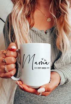 a woman holding a coffee mug that says mama est 2013