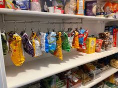 several bags of food hanging from hooks in a store display case with other items on the shelves