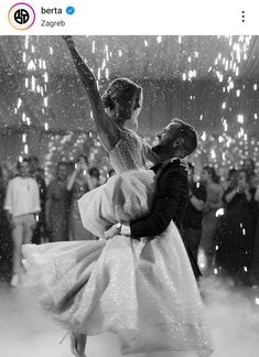 a man and woman dancing in the rain with sparkles all around their feet,