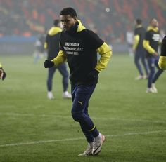 a man is running on the field with other people in the background wearing yellow and black jackets