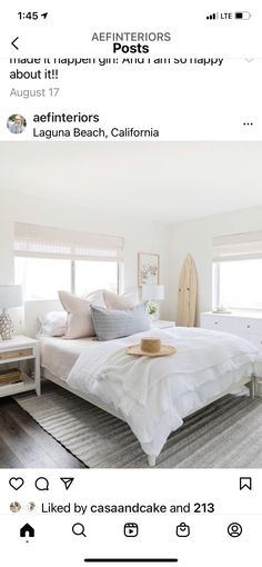 a bedroom with white furniture and pillows on the bed, in front of two windows