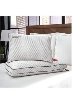 a bed with white sheets and pillows on top of it in front of a window