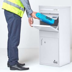 a man opening a mailbox with a blue bottle in it and his hand is on top of the box