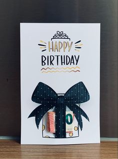 a happy birthday card with a black bow and some type of candy in front of it