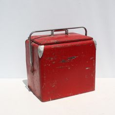 an old red metal box sitting on top of a white table