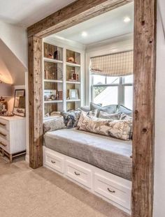 a large window seat in the middle of a living room with built - in bookshelves