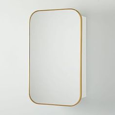 a mirror mounted to the wall with a gold frame and an empty shelf below it