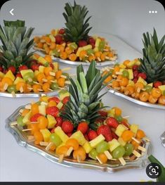 fruit platters with pineapples, strawberries, oranges and grapes on them