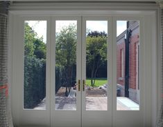 an open patio door leading to a back yard with trees and bushes in the background