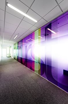 an empty office space with purple and green wall art on the walls, along with carpeted flooring