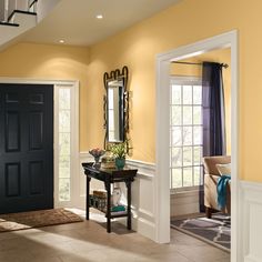 an entry way with yellow walls and black doors, white trimmings, and a mirror on the wall