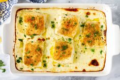 a casserole dish with cheese and parsley in it on a marble surface