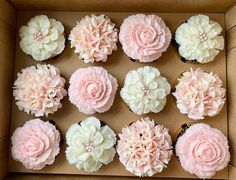 a box filled with cupcakes covered in pink and white frosting flower decorations