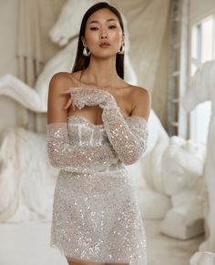 a woman in a white dress posing for the camera with her hands on her chest