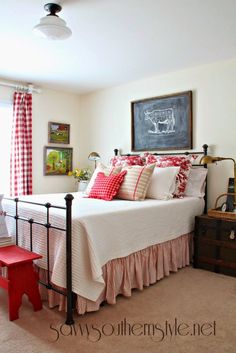 a bed with red and white pillows in a bedroom next to a chalkboard on the wall