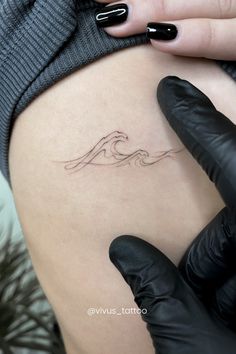 a woman's thigh with a small wave tattoo on her left side ribcage