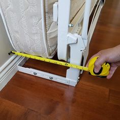 a person holding a measuring tape next to a mattress