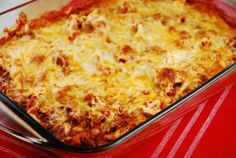 a cheesy casserole in a glass dish on a red tablecloth