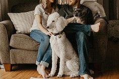 a man and woman sitting on a couch with two dogs