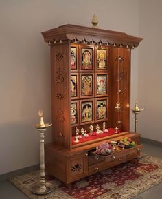 a wooden cabinet with pictures on it and candles in the corner next to it, sitting on top of a rug