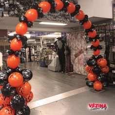 an orange and black balloon arch in a store