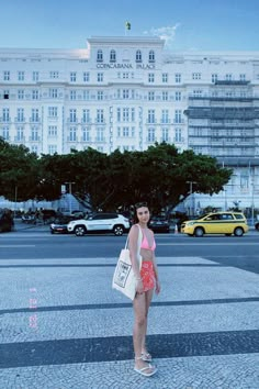 a woman standing in the middle of an empty parking lot with a building in the background