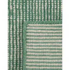 two green and white striped rugs on top of each other, one with a square in the middle