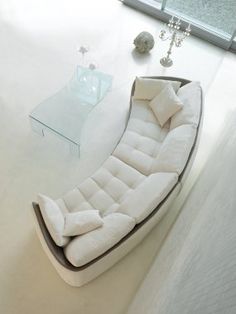 a white couch sitting on top of a floor next to a glass table and window