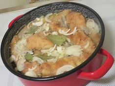 a red pot filled with food on top of a white tablecloth covered countertop