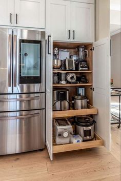 an organized kitchen with stainless steel appliances and white cabinetry, along with wooden flooring