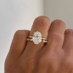 a woman's hand with a diamond ring on top of her finger and an engagement band