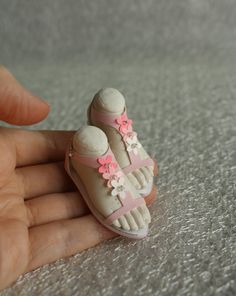 a hand is holding a tiny doll shoe