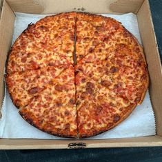 a large pizza in a cardboard box with one slice missing from the pizza and another half has cheese on it