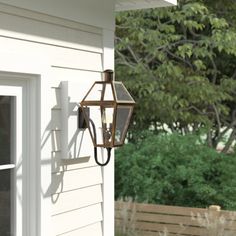 a light hanging from the side of a house next to a window and door with trees in the background