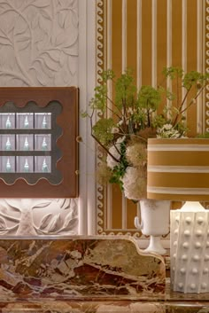 vases with flowers and greenery in front of decorative wall paneling on display