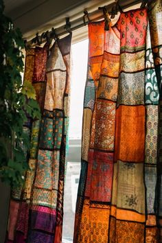 the curtains are hanging in front of the window with many different colored fabrics on them