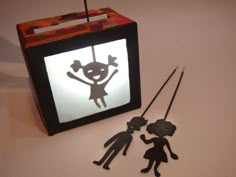 a paper cut out of a girl and boy on a string next to a box