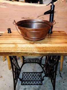 an old fashioned sewing machine is sitting on a table next to a large metal bowl