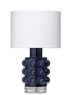 a blue glass table lamp with a white shade on the top and bottom part of it