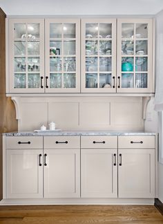 a kitchen with white cabinets and marble counter tops