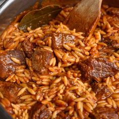 a pot full of rice and meat with a wooden spoon sticking out of the top