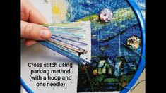 someone is stitching pictures on a piece of fabric with needle and thread in their hands