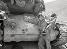 a man standing next to a tank in the desert