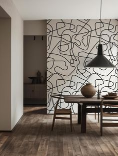 a dining room with wood flooring and an artistic wallpaper design behind the table