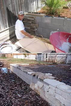 a man holding a surfboard next to a pile of rocks and gravel in his backyard