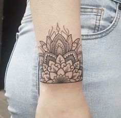 a woman's arm with a black and white tattoo design on the left wrist