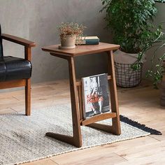 a small table with a magazine on it next to a chair and potted plant