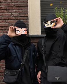 two people wearing masks and holding up cell phones