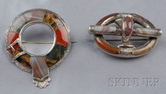 two brooches, one in the shape of a boat wheel