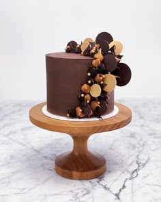 there is a chocolate cake with gold decorations on the top and bottom, sitting on a wooden stand